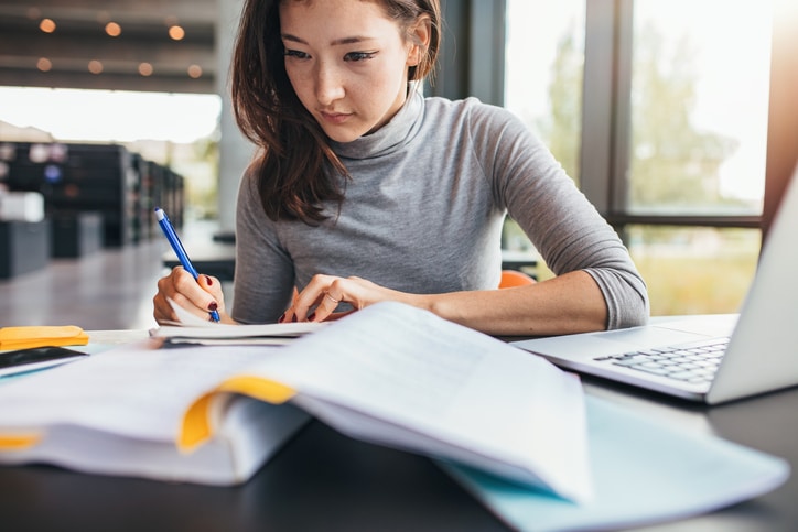 Student taking notes from textbook